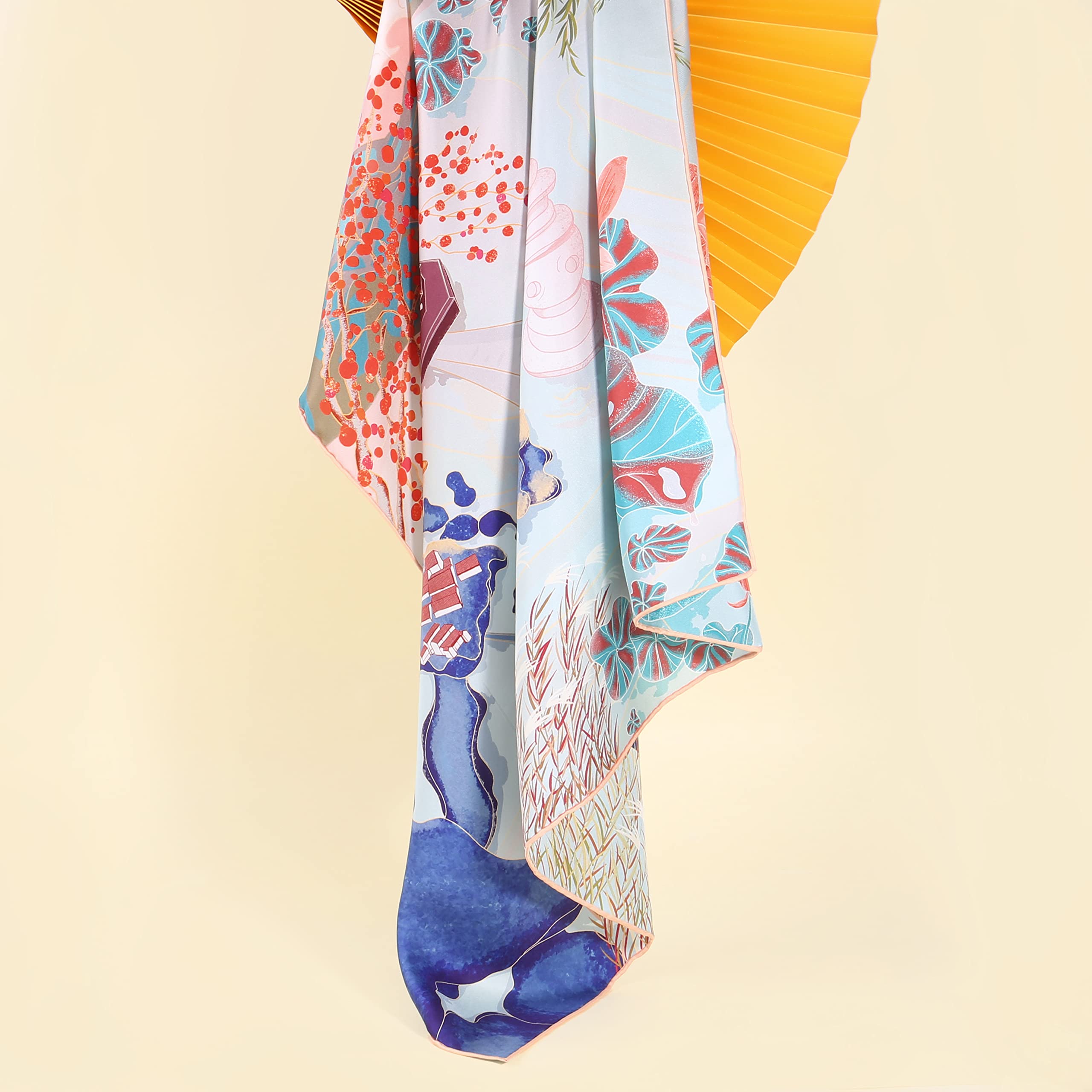 The lotus and pagoda silk scarf hanging in folds against a yellow fan backdrop