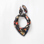 Black cat print silk knotted into a loop, pointed corner showing the pale grey border