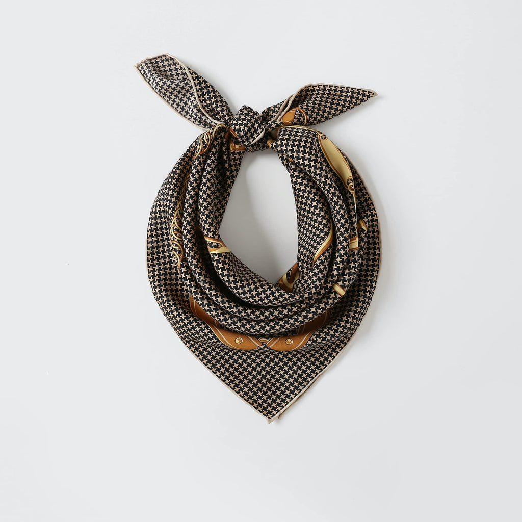 Houndstooth silk neckerchief knotted at the throat over a black top