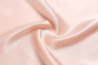 Macro of blush pink silk charmeuse swirling into a soft centre fold