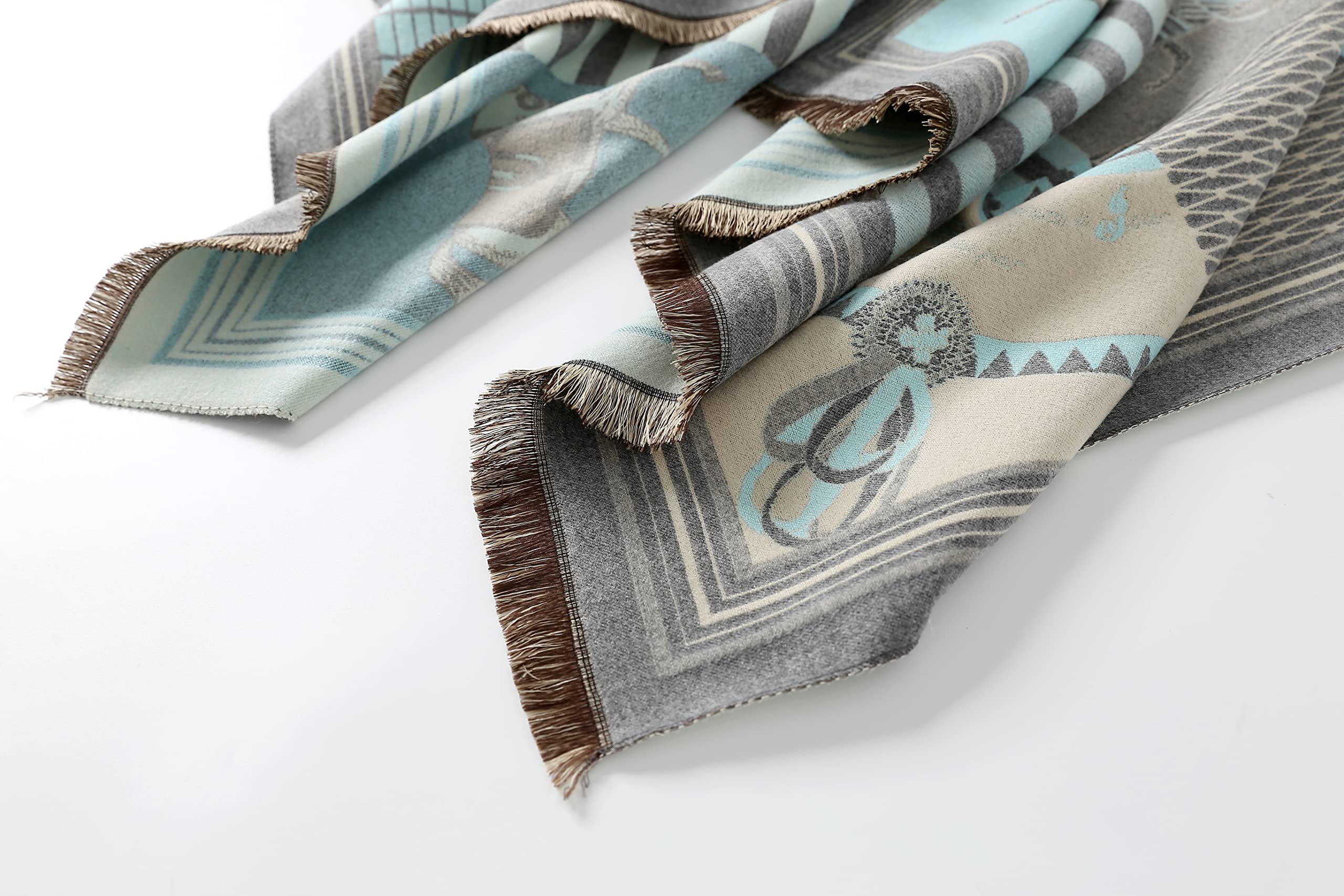 The pale blue shawl laid out in a loose S shape showing the brown fringe along both ends