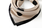 Greige dotted silk coiled into a collar with the black border corner hanging in front