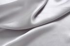 Macro of cloud grey silk charmeuse in soft waves, unprinted with a bright satin lustre