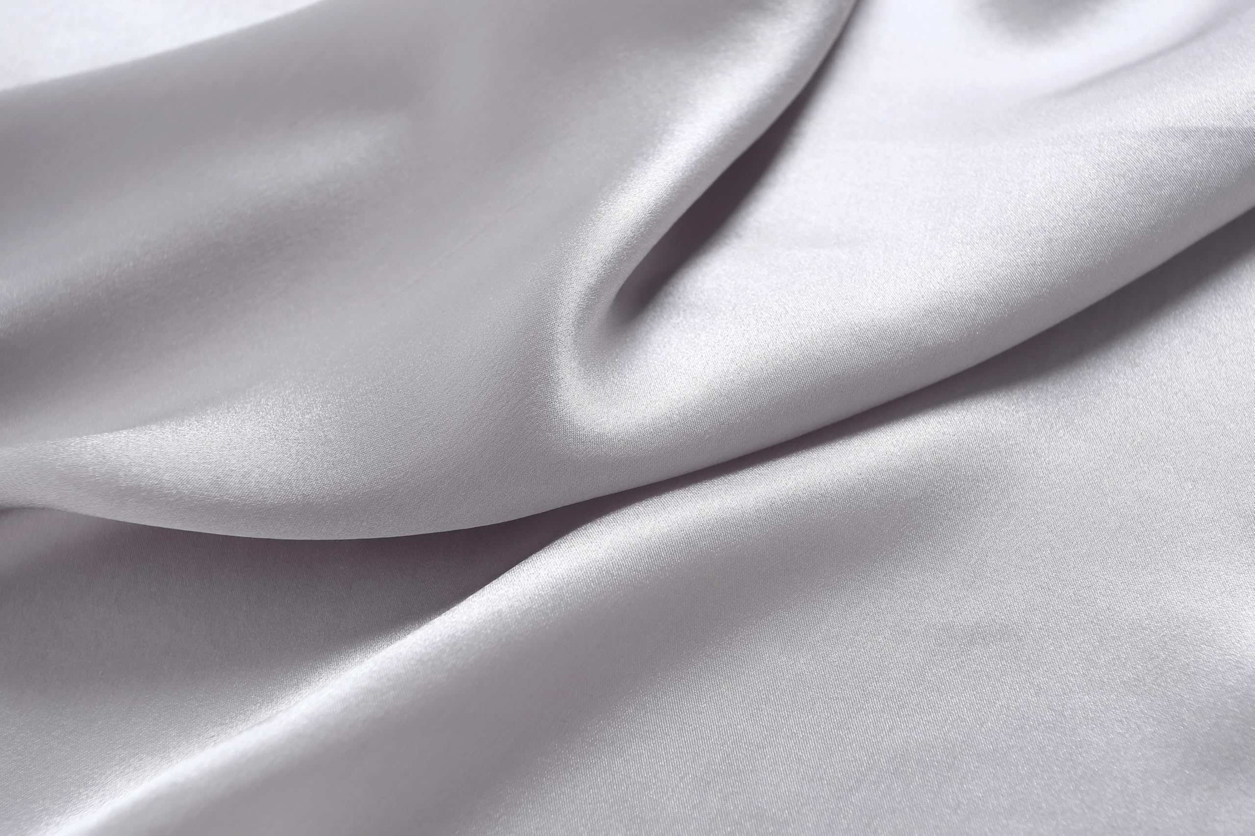 Macro of cloud grey silk charmeuse in soft waves, unprinted with a bright satin lustre