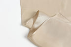 Champagne beige silk lifted at the edge, showing the narrow rolled hem and care label