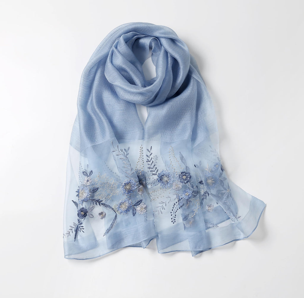 Denim blue silk blend shawl laid flat with blue floral and trailing frond embroidery across both ends