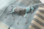 Macro of a single saddled horse motif woven in cream and grey on the pale blue ground