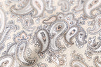Macro of the print, fine taupe and apricot paisley teardrops on warm cream silk