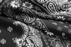 Macro of white paisley and daisy motifs printed on glossy black silk folds