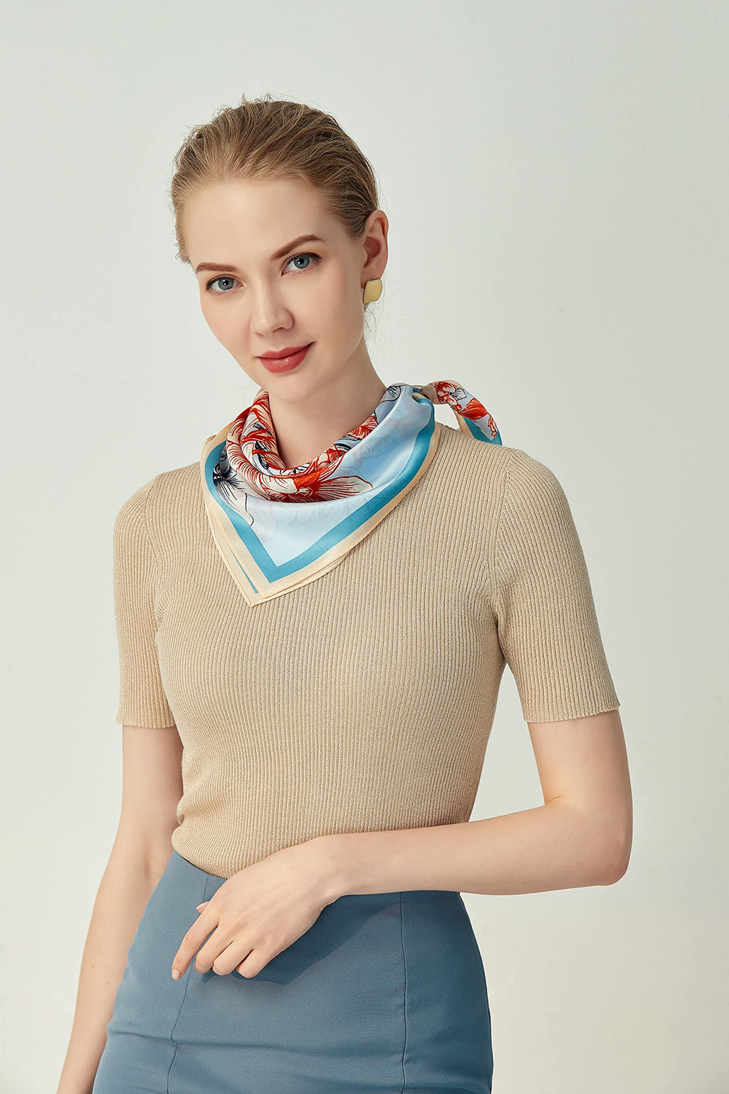 Woman in a beige top wearing the coral and blue square folded into a V at the neck