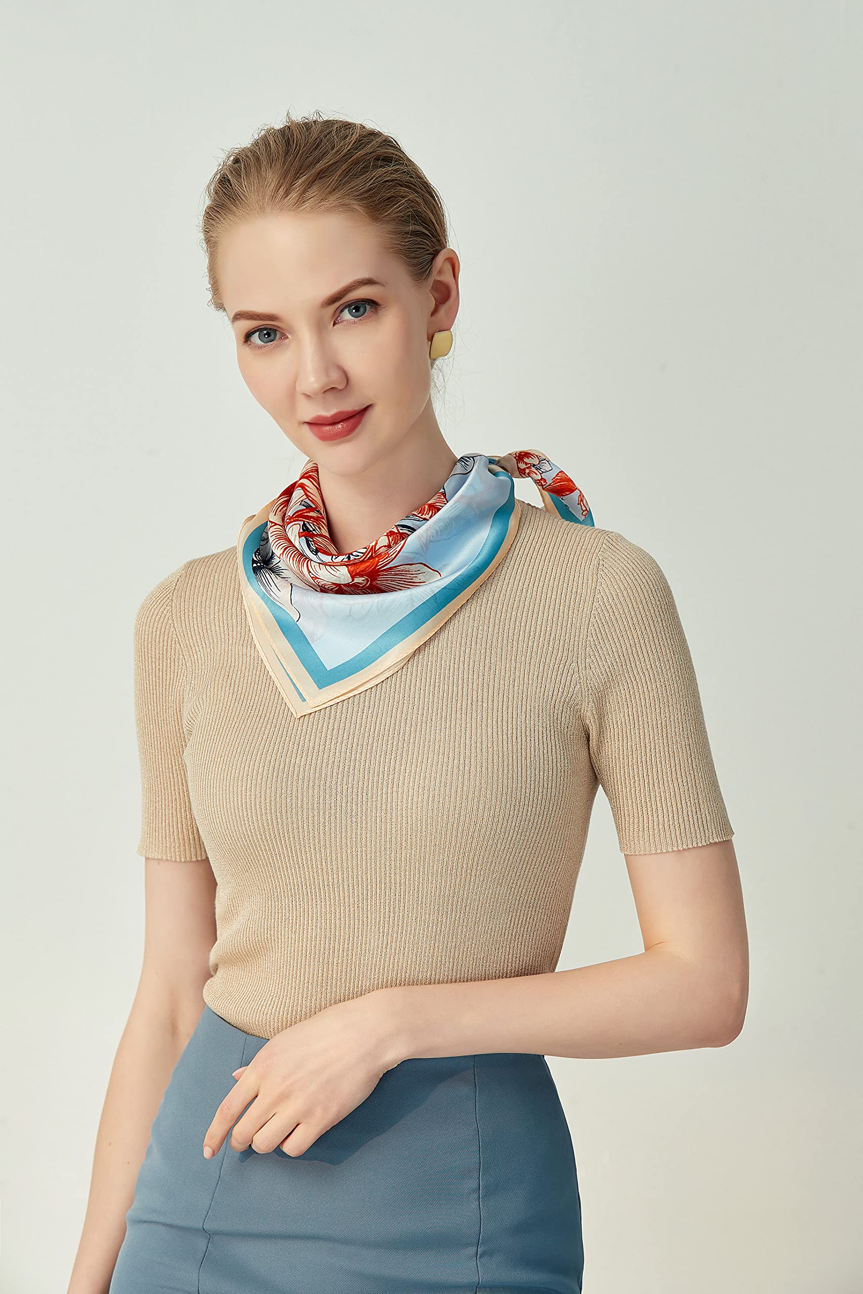 Woman in a beige top wearing the coral and blue square folded into a V at the neck