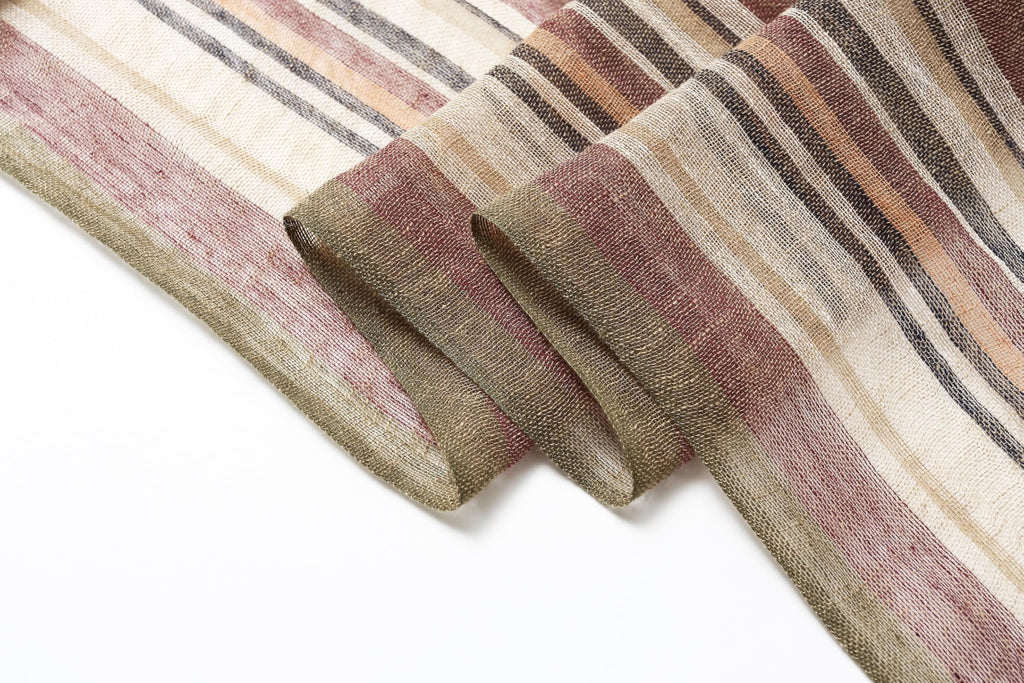 Close view of the folded scarf edge showing the loose weave and rose brown and olive stripes