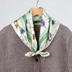 Wildflower square tied at the collar of a brown wool coat on a hanger