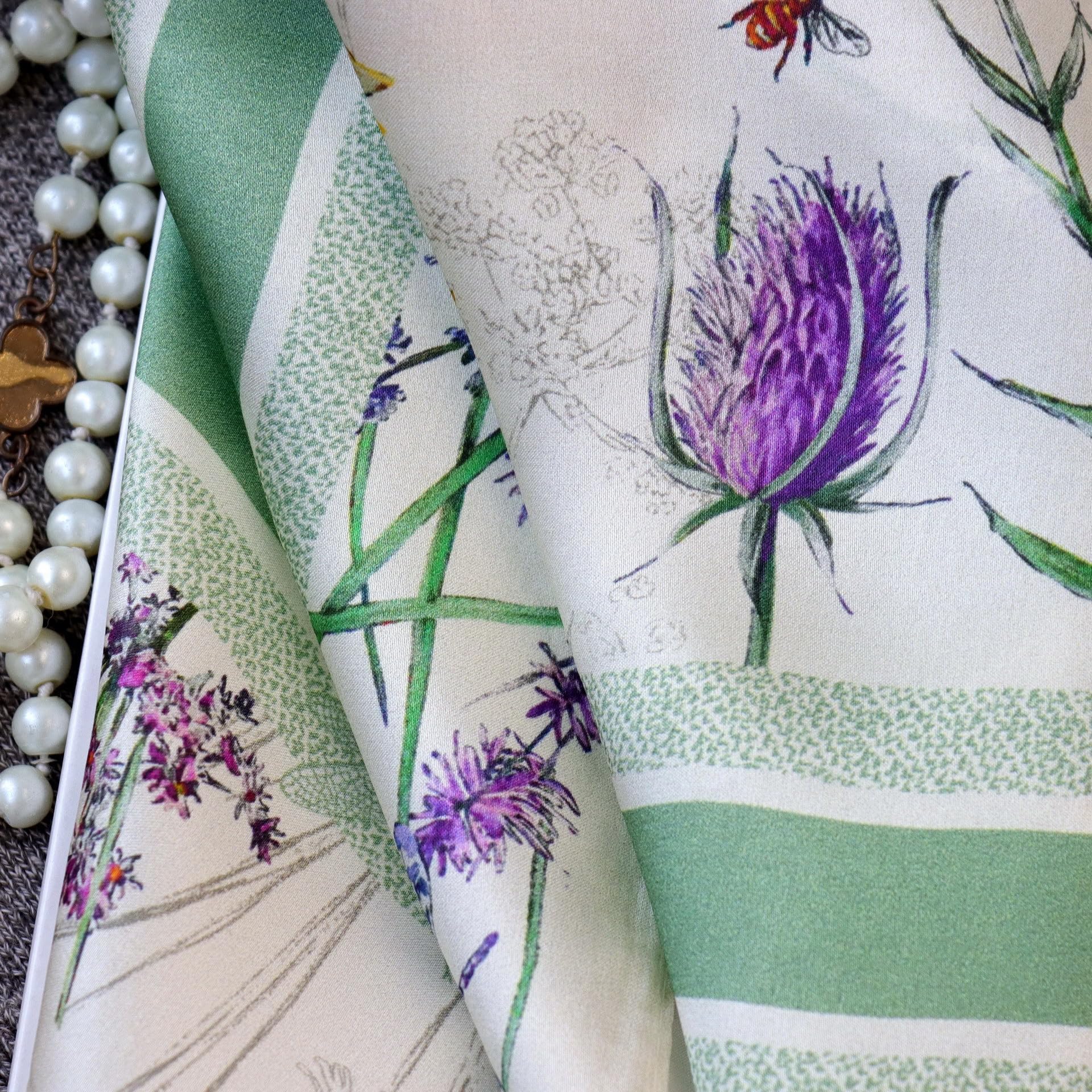 Close-up of a purple thistle and the sage green stripe band on ivory silk