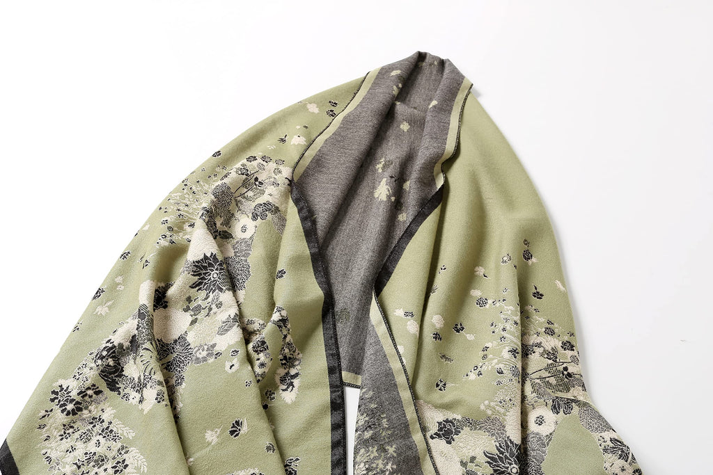 The sage shawl folded over itself showing the grey reverse running alongside the printed face
