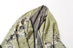 The sage shawl folded over itself showing the grey reverse running alongside the printed face