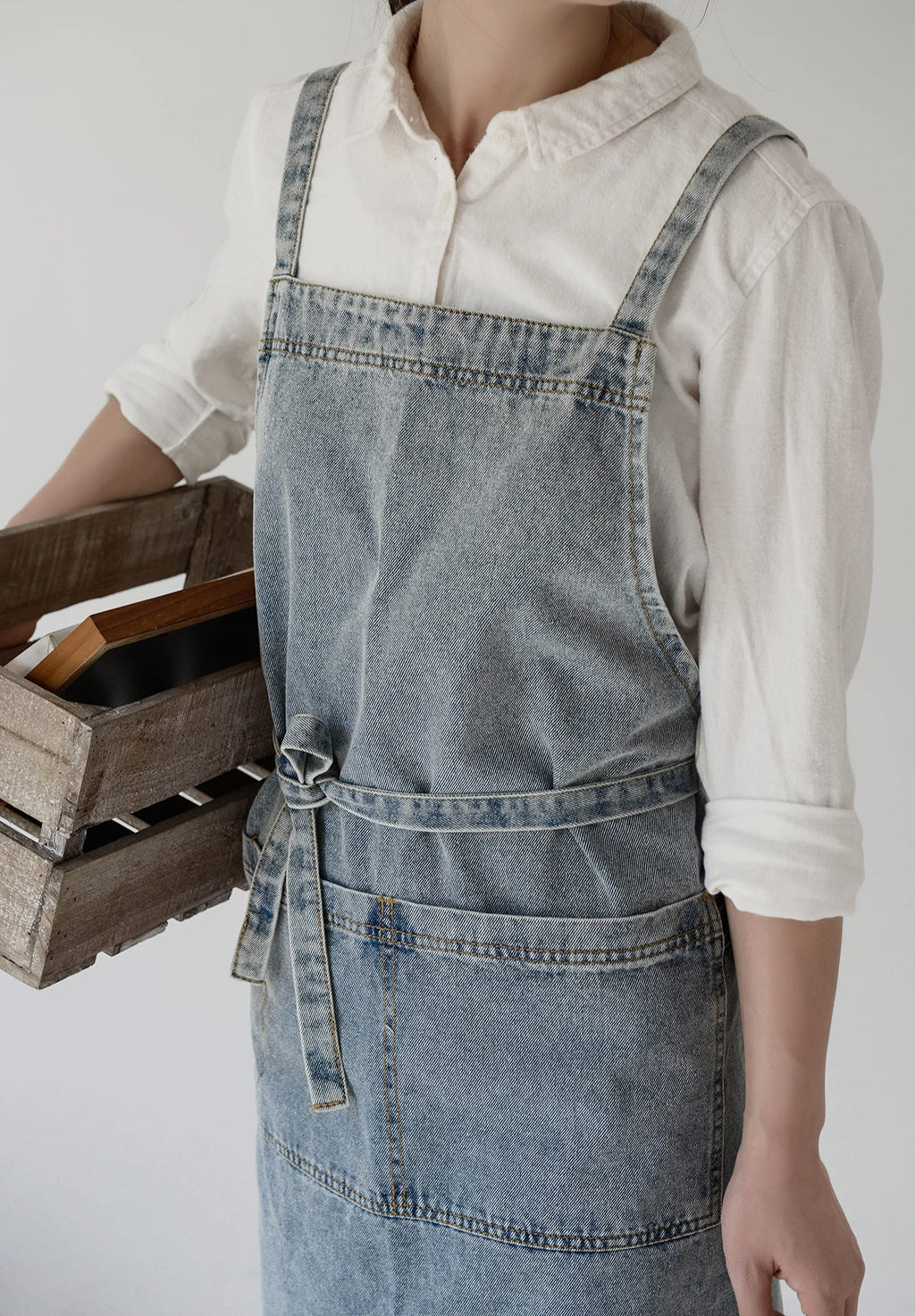 Close view of the washed denim front pocket and the waist tie knotted at the front