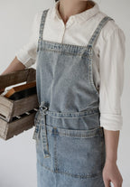 Close view of the washed denim front pocket and the waist tie knotted at the front
