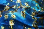 Close-up of white blossom and dark branches on rippled cerulean silk