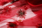 Close up of beaded red flowers stitched onto the sheer panel