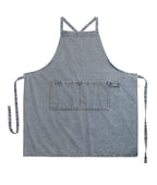 Pale washed denim apron laid flat showing the front pocket and the long ties