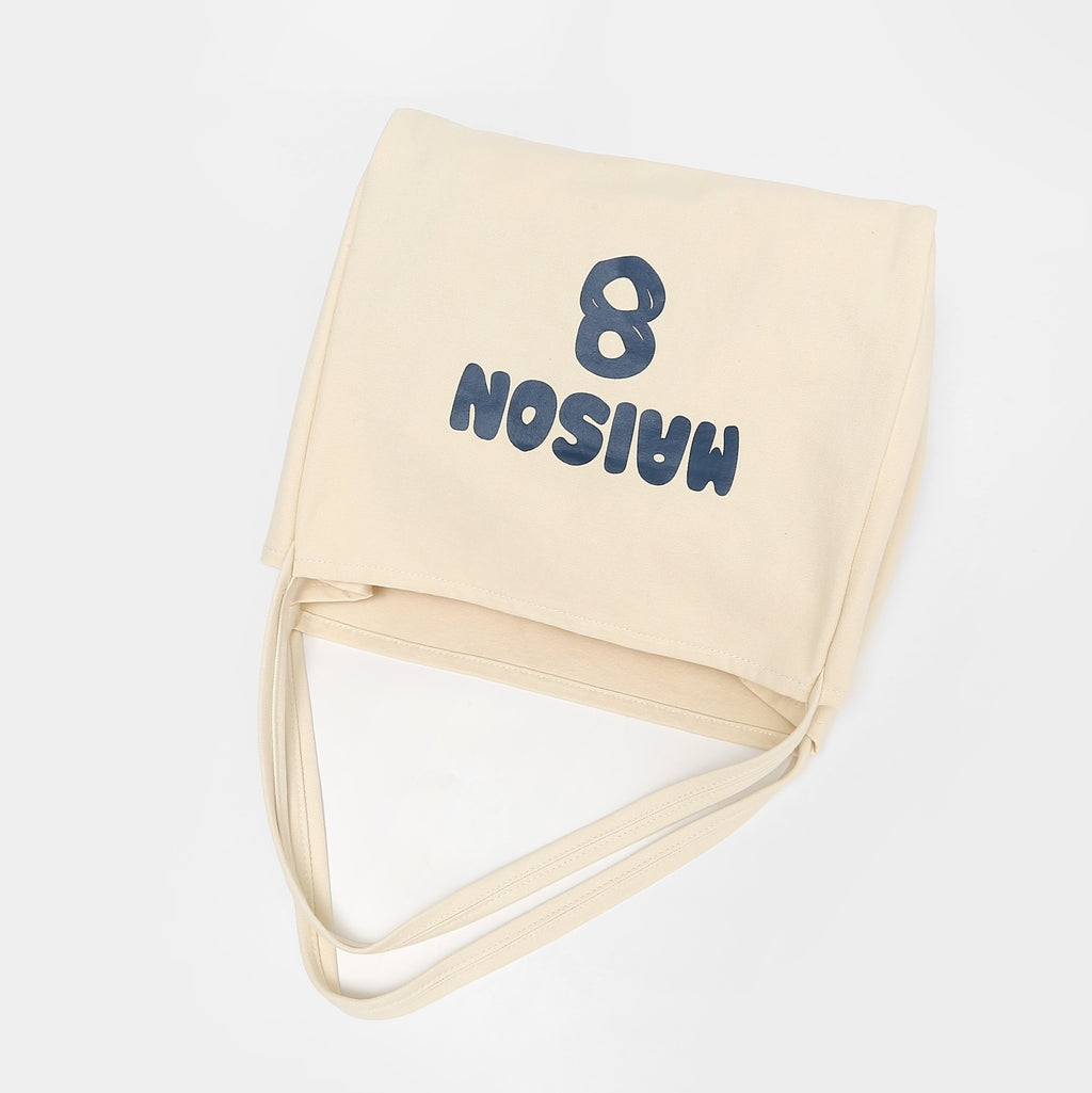 Cream canvas tote bag folded with shoulder straps