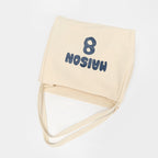 Cream canvas tote bag folded with shoulder straps