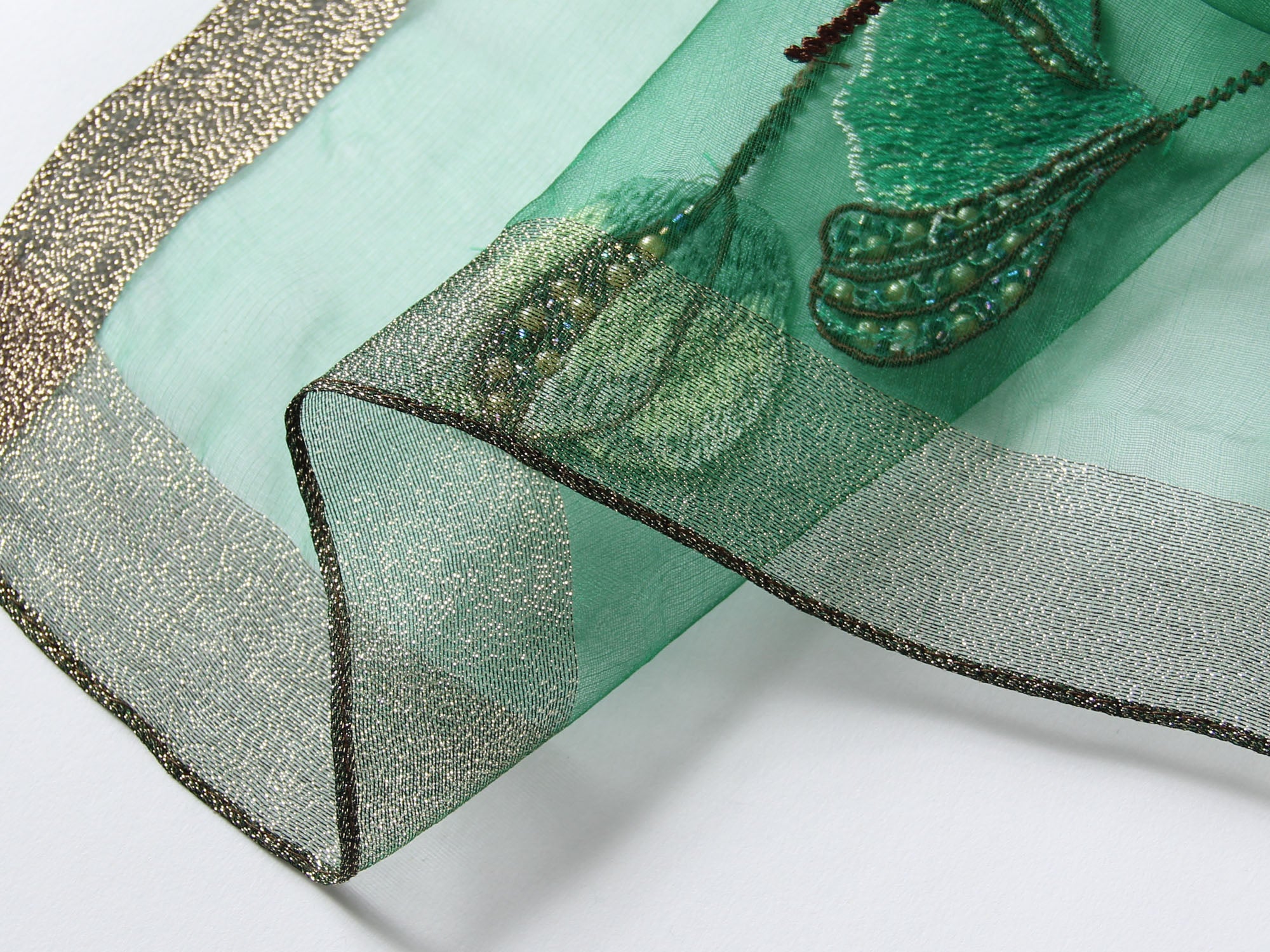 Close-up of embroidered poppies with beaded centers on gray scarf