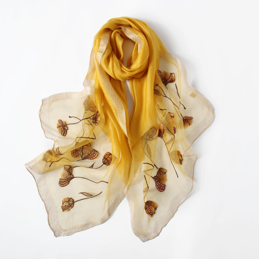 Close-up of embroidered poppies with beaded centers on champagne scarf