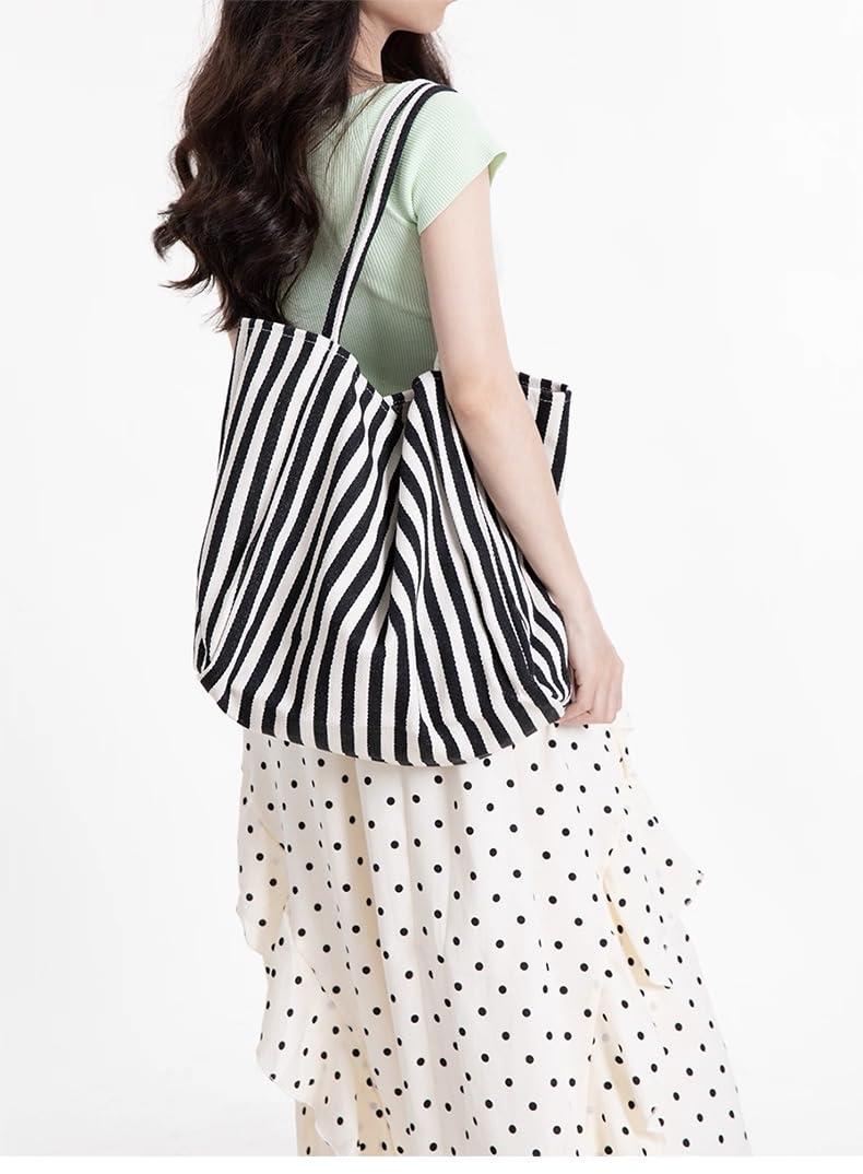 Woman carrying the navy stripe canvas tote on one shoulder over a green top